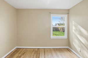 Unfurnished room featuring light wood finished floors and baseboards