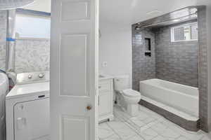 Full bathroom featuring washer / clothes dryer, vanity, light marble finish flooring, and  shower combination