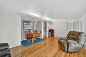 Living area with a textured ceiling, light wood-style flooring, and stairway