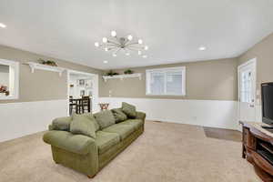 Living room featuring wainscoting, light carpet, a textured ceiling, recessed lighting, and a chandelier