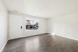 Unfurnished room featuring dark wood-type flooring and baseboards