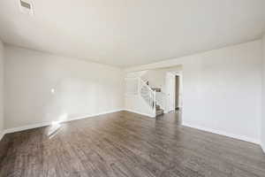 Empty room with stairs and dark wood-type flooring