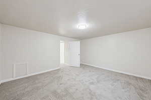 Empty room featuring a textured ceiling and light carpet