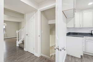 Kitchen featuring white cabinets, dark wood-style floors, dark stone countertops, and tasteful backsplash