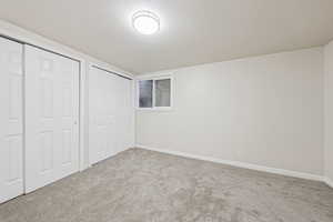 Unfurnished bedroom with a textured ceiling, multiple closets, and carpet floors