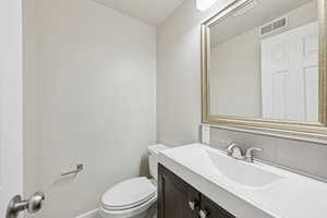 Half bathroom featuring vanity and toilet