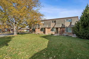 Colonial-style house with brick siding, a front lawn, and roof with shingles