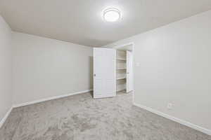 Unfurnished bedroom featuring a textured ceiling, carpet floors, and a walk in closet