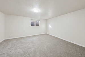 Empty room with light colored carpet and a textured ceiling