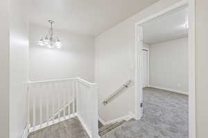 Staircase with carpet floors and a chandelier