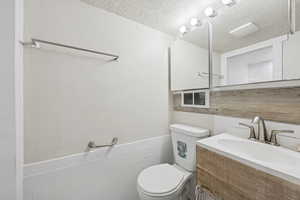 Half bath with a textured wall, vanity, and a textured ceiling