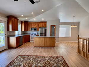 Kitchen featuring stainless steel appliances, recessed lighting, a kitchen island, hanging light fixtures, and brown cabinets