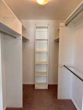 Master walk in closet featuring dark colored carpet