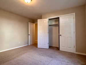 Unfurnished bedroom featuring light carpet, a closet, and a textured ceiling