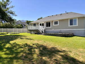Back of property with a wooden deck, stucco siding, a shingled roof, and stairway