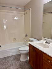 Bathroom with vanity, washtub / shower combination, and dark tile patterned flooring