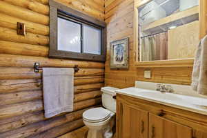 Bathroom featuring curtained shower, vanity, and rustic walls