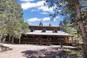 View of front facade featuring a metal roof, log exterior, and covered porch