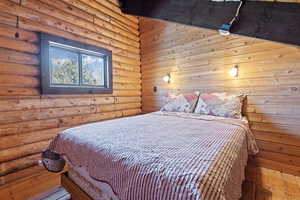 Bedroom featuring log walls and wood-type flooring