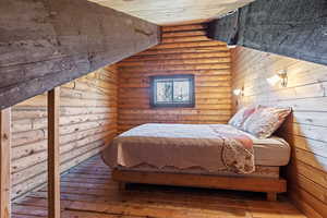 Bedroom featuring rustic walls, a sauna / steam room, wood-type flooring, wooden ceiling, and vaulted ceiling