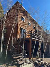 Rear view of house featuring stairs, a wooden deck, and log exterior