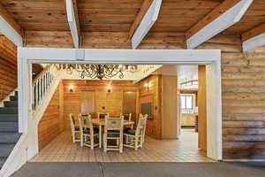 Dining room with log walls, light tile patterned floors, stairway, a wooden ceiling with exposed beams, and light carpet