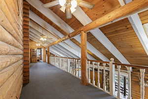 Corridor featuring rustic walls, healthy amount of natural light, carpet flooring, and wooden ceiling