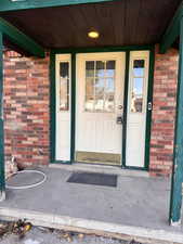 Entrance to property featuring brick siding and a porch
