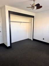 Unfurnished bedroom featuring a textured ceiling, a ceiling fan, a closet, and dark colored carpet