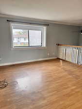 Unfurnished room featuring ornamental molding, light wood-style flooring, a ceiling fan, and a textured ceiling