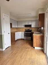 Kitchen with appliances with stainless steel finishes, light wood-style floors, and light countertops