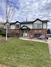 View of front of home with brick siding, a front yard, and stucco siding