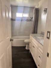 Full bath featuring vanity, shower / bathtub combination with curtain, and dark wood-style floors