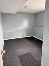Carpeted empty room with a textured ceiling and baseboards