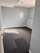 Carpeted empty room featuring baseboards and a textured ceiling