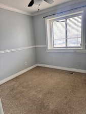 Carpeted empty room featuring crown molding, a textured ceiling, and ceiling fan