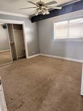 Unfurnished bedroom with a textured ceiling, carpet, a closet, crown molding, and ceiling fan