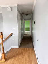 Hallway featuring light wood-style flooring, ornamental molding, and a textured ceiling