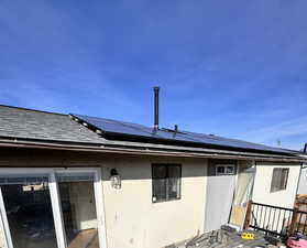 Back of house with roof mounted solar panels and stucco siding