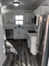 Kitchen with stainless steel appliances, light countertops, white cabinetry, dark wood finished floors, and a textured ceiling