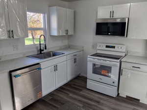 Kitchen with appliances with stainless steel finishes, white cabinetry, and dark wood-style floors