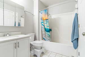 Bathroom with light tile patterned floors, vanity, and shower / bath combo with shower curtain