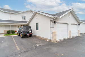 View of property exterior featuring stucco siding, roof with shingles, and brick siding