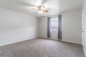 Carpeted empty room featuring ceiling fan and a textured ceiling