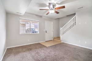 Foyer entrance with light carpet, light tile patterned floors, a textured ceiling, ceiling fan, and stairs