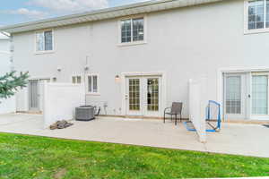 Rear view of house with stucco siding, a patio, and a lawn