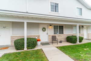 Property entrance with brick siding, stucco siding, and a lawn