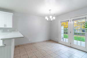 Unfurnished dining area featuring light tile patterned floors, a chandelier, and a textured ceiling