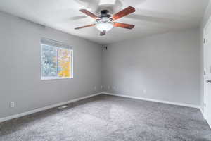 Carpeted spare room featuring a textured ceiling and a ceiling fan
