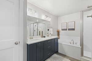 Bathroom featuring double vanity, a stall shower, light wood finished floors, and a bath